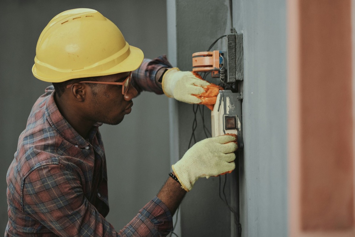 Electrician in a hard hat and safety gloves at work